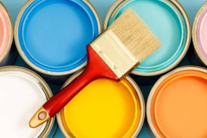 Open cans of paint and a paint brush that show an example of the painting colors that Pinellas County painters can provide. 