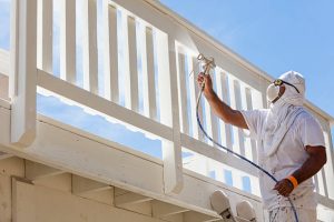 A professional painter in Pinellas County sprays paint on an exterior building railing. 