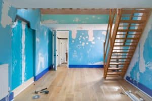 The photo is of an interior room in a building with a staircase off to the side. The room has been messily painted blue and needs to be fixed. This is an example of a paint job that can be fixed by professional Pinellas County painters near me. 