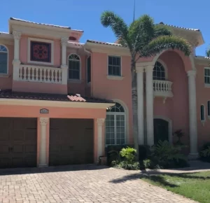 Exterior of a house painted by the best house painters in Pinellas county. House is a salmon color with cream columns and railings. 