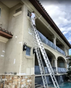 Man on ladder from best Pinellas County Painters near me painting the exterior of a building.